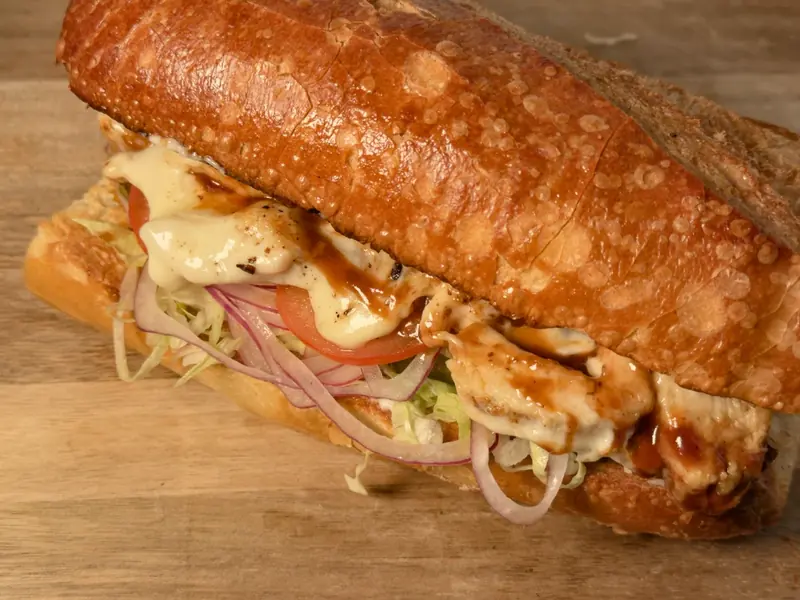 The Hood on a crusty roll, layered with barbecue chicken, melted cheese, shredded iceberg lettuce, red onion and sliced tomato.
